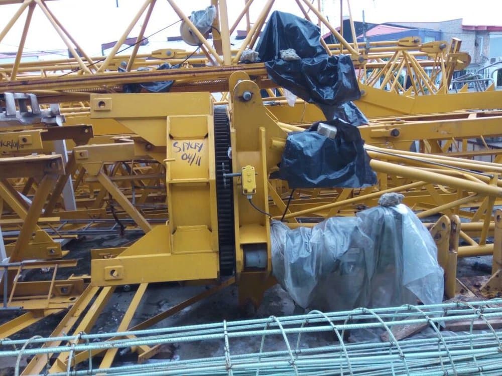 Tower crane components and heavy machinery at a construction staging yard